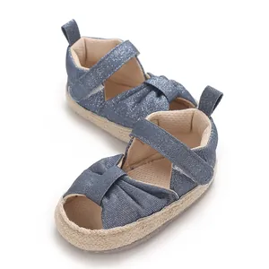 Close-up of blue denim baby sandals with soft woven sole and velcro strap