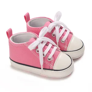 Pink canvas baby sneakers with white laces and soft soles for infants aged 0-1 year.