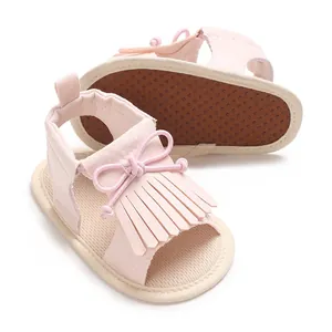 Weiche rosa Sandalen für Baby-Mädchen mit Fransen und Schleifen-Detail auf weißem Grund.