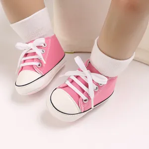 Close-up detail of pink baby canvas sneakers with white laces for 0-1 year old infants.