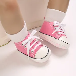 Close-up of pink baby canvas sneakers with white laces worn by a baby mannequin feet