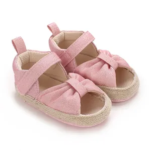 Close-up of pink shimmering baby sandals with knotted bow and adjustable strap