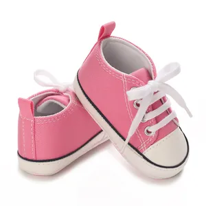 Detailed view of pink baby canvas sneakers with white laces and durable rubber toe