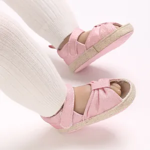 Close-up of pink soft-sole baby sandals with shimmery fabric and hook-and-loop straps.