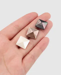 Detail view of premium natural iridescent square pyramid shell buttons on a hand