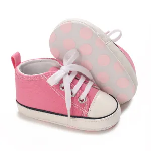 Detail view of pink baby canvas sneakers with white laces and polka dot sole pattern