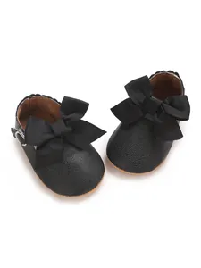 Detail of black faux leather baby princess shoes with a large grosgrain ribbon bow