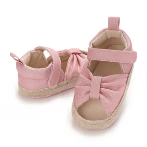 Detail view of pink baby sandals with a shimmering fabric and a large decorative bow.
