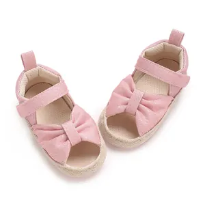 Charming pink infant sandals featuring a large decorative bow and soft breathable sole