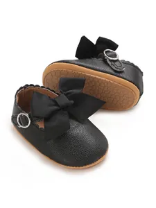 Close-up of black PU leather baby princess shoes with ribbon bow and buckle