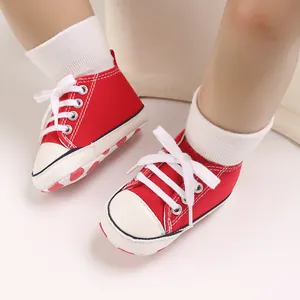 Close-up of red baby canvas sneakers with white laces and polka dot sole pattern