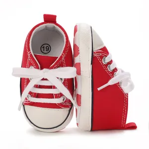 Red canvas baby sneakers with white laces and cute heart pattern sole side details.