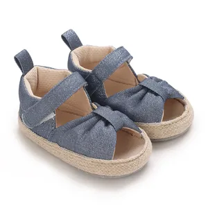 Detailed view of blue denim baby sandals with soft espadrille sole and knot design.