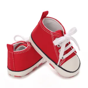 Detailed side view of red canvas baby sneakers with white laces for infants