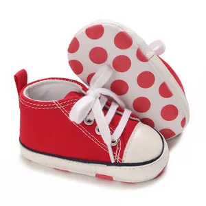 Red baby canvas sneakers with white laces and polka dot anti-slip sole for infants.
