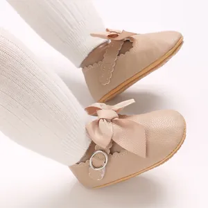 Close-up view of beige baby princess shoes with ribbon bow detail and soft sole