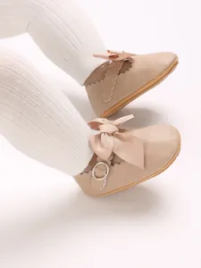 Close-up of beige PU leather baby Mary Jane shoes with bow detail and scalloped edges.