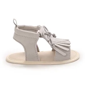 Professional side view of grey infant tassel sandals with soft sole and bow accent detailing.