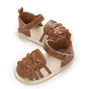 Gros plan sur des sandales d'apprentissage marron tressées avec velcro pour bébé.