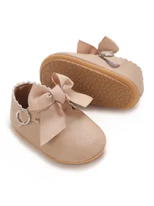 Close-up of beige baby girl princess shoes with a large ribbon bow and soft sole
