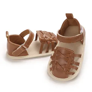 Gros plan de sandales marron pour bébé avec brides en cuir tressé et semelles