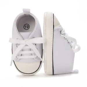 Close-up of white infant canvas sneakers showing the shoe side and front detail.