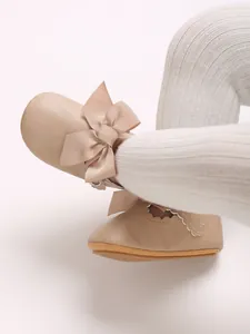 Detail view of beige PU leather baby princess shoes featuring a large decorative bow