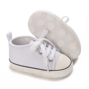 Close-up of white infant canvas sneakers showing the anti-slip polka dot patterned sole
