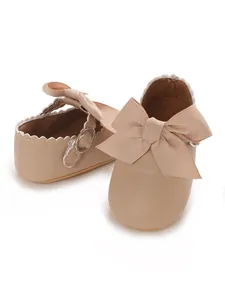 Detail view of beige baby girl PU leather princess shoes with a large ribbon bow.