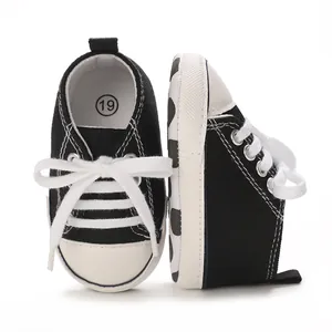 Side and front view detail of classic black and white canvas sneakers for infant babies