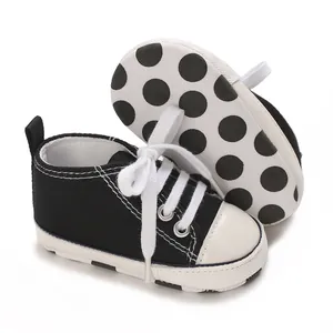 Close-up of black baby canvas sneakers featuring a white polka-dot anti-slip sole