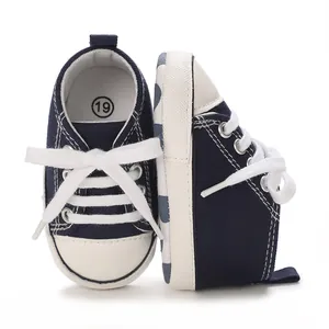 Detailed view of dark blue baby canvas sneakers with white laces for 0-1 year old infants.