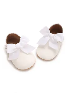 Detailed view of elegant white baby girl princess shoes with large ribbon bows