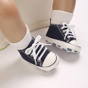 Close-up of navy blue baby canvas sneakers with white laces on infant feet.
