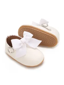 Detail of white PU baby princess shoes with big bows and non-slip soles for girls