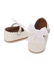 Detailed view of white PU baby princess shoes with a large ribbon bow and scalloped edges.