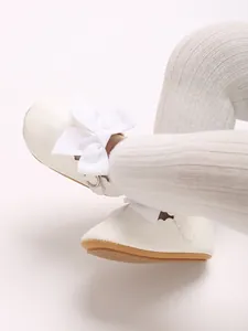 Detailed close-up of elegant white PU leather baby princess shoes with ribbon bow detail