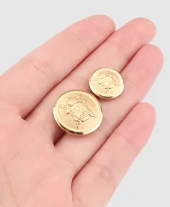 Detaillierte Makroansicht von zwei goldenen Messingknöpfen mit Vintage-Wappen auf Hand