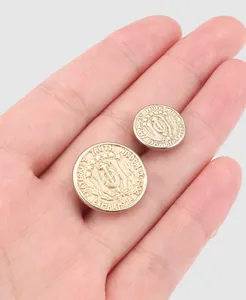 High-end vintage Japanese copper buttons with heraldic engraving held in palm for scale