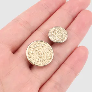 Premium vintage gold-colored engraved copper buttons held in hand for clothing detail.