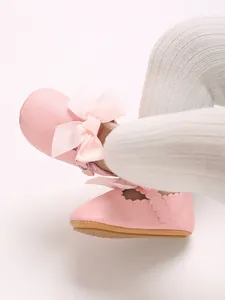 Close-up view of elegant pink PU baby princess shoes with ribbon bow detail on feet