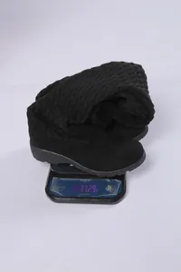 Detalle de medición de peso de botas por encima de la rodilla de punto negro en báscula