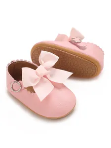 Close-up of pink PU leather baby princess shoes with large bow and anti-slip rubber sole