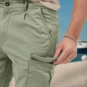 Close-up of side pocket detail on men's sage green multi-pocket cargo pants