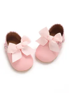Close-up of pink PU baby princess shoes featuring large grosgrain ribbon bows