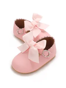 Close-up of pink PU leather baby princess shoes with a large ribbon bow detail