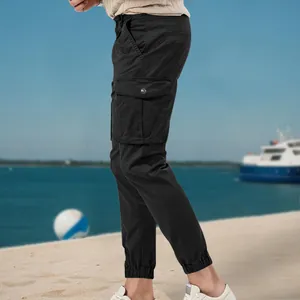 Detail of men's black multi-pocket cargo jogger pants in a casual beach setting.