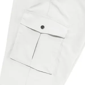 Detail of white cargo pants featuring a flap pocket with a metal button closure.