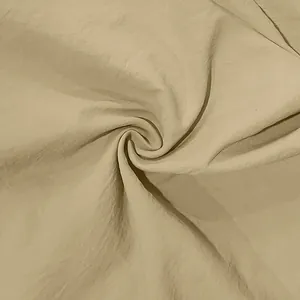 Macro view of light khaki vintage linen fabric showing breathable crinkled texture detail