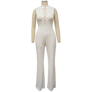 Close-up view of a white sleeveless jumpsuit with lace-up gold chain detail and wide leg cut.